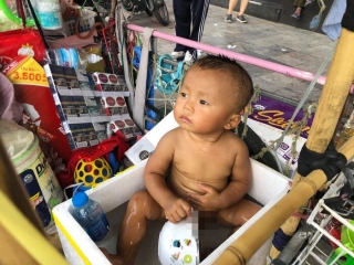 Hình ảnh cháu bé ngồi trong thùng xốp đựng nước giữa nắng nóng khiến nhiều người quan tâm.