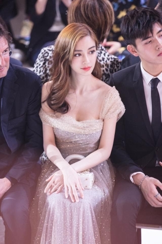 Trong kiểu váy lấp lánh, Angelababy “lấp ló” vòng một trễ vai cùng kiểu tóc uốn cổ điển nổi bật trên hàng ghế đầu khi xem show Dior