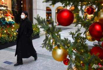 Một phụ nữ đeo khẩu trang đi qua cây thông Noel ở London ngày 22/12ảnh: AP