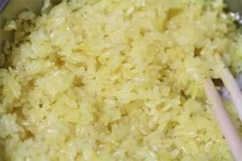 Vớt gạo ra cho ráo nước, xới đều cho màu nghệ được đều. Nếu dùng tinh nghệ thì ở dưới hay có màu vàng đậm hơn do nghệ lắng xuống dưới. Cho vào chõ đồ chín.