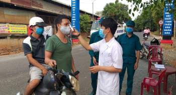 Lực lượng chức năng kiểm tra thân nhiệt người dân đi qua chốt chặn kiểm soát dịch Covid-19 trên địa bàn tỉnh Bình Phước.